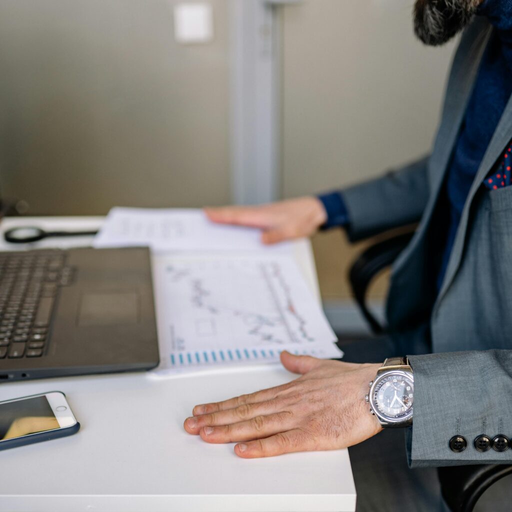 Businessman analyzing charts and graphs at his desk with a laptop and smartphone.